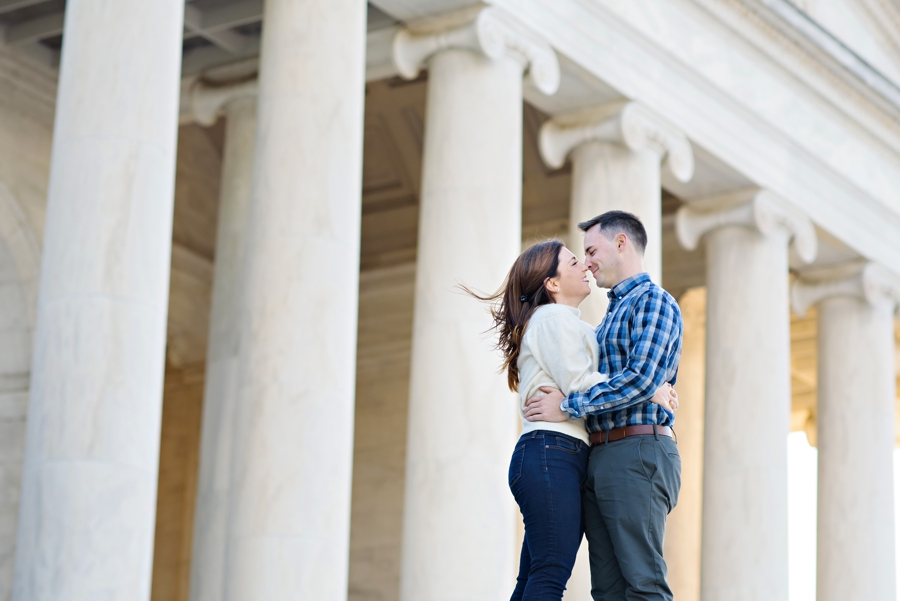 An engaged couple hug in front of the columns of the lincoln memorial in DC.